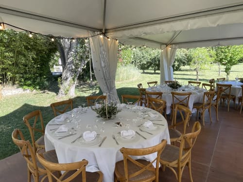 Réception de mariage en plein air aux Jardins Du Soleil, Avignon avec tables rondes, chaises dossier croisé sous chapiteau