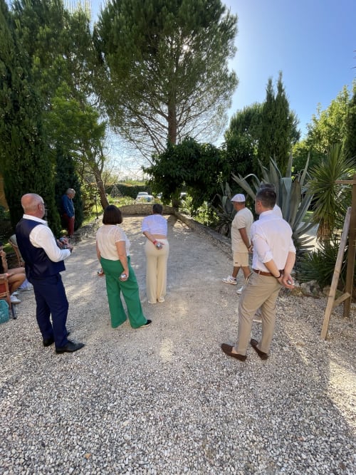 Des invités réunis sur une allée du jardin aux Jardins Du Soleil à Avignon, entourés de cyprès et de végétation luxuriante