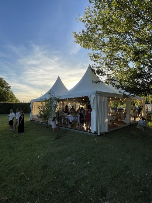 Élégante tente blanche pour un événement aux Jardins Du Soleil à Avignon, avec des convives dînant en plein air au crépuscule