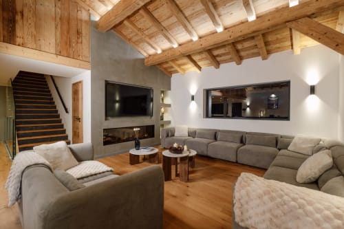 Spacieux séjour du Chalet Magy Altitudia avec poutres apparentes, sièges confortables, cheminée et vue montagne