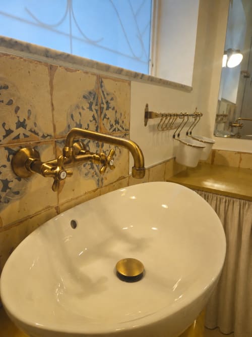 Elegant bathroom sink with gold fixtures and blue patterned tiles at Pura Vita Apartments in Monopoli