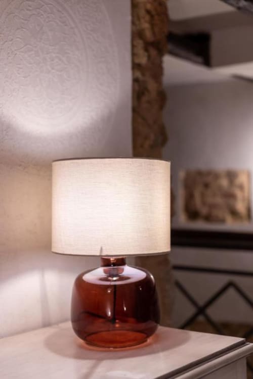 Elegante lampada da tavolo con base in vetro ambrato e paralume in lino color crema nella camera di lusso di un appartamento a Palermo
