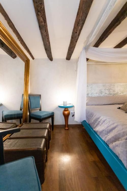 Camera da letto spaziosa ad Oltre Exclusive a Palermo con travi in legno a vista, dettagli turchesi, pavimenti in legno e design moderno