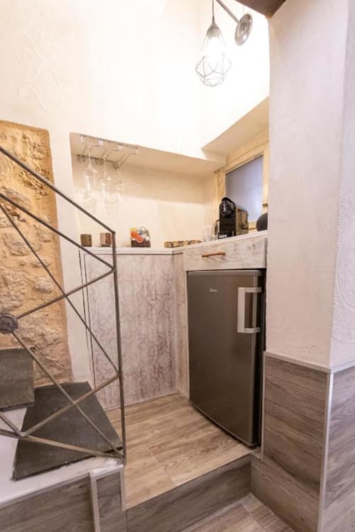 Cucina moderna con frigorifero in acciaio inossidabile, armadiature in legno e ringhiera in pietra nella boutique hotel di Palermo