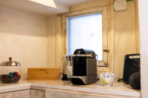 Angolo cottura del caveau con macchina Nespresso nera, arredamento in legno e finestra luminosa nel B&B di Palermo
