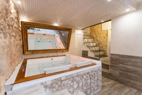 Lussuoso bagno spa dell'Oltre Exclusive di Palermo con vasca idromassaggio, finiture in legno, pareti in pietra e specchio