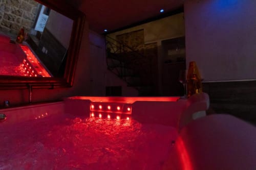 Vasca idromassaggio illuminata in rosso presso Oltre Exclusive Caveau a Palermo, con getti luminosi e elegante atmosfera spa in appartamento