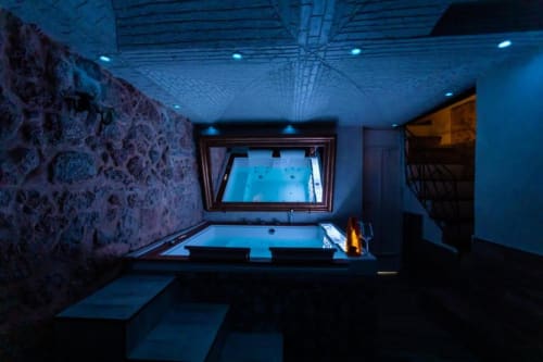 Lussuoso bagno spa a Palermo con vasca idromassaggio illuminata, illuminazione ambientale blu, carta da parati decorativa e vista da finestra
