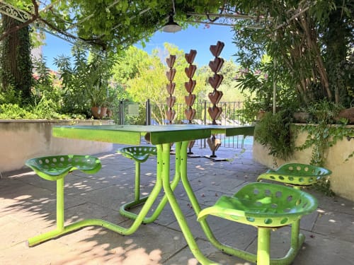 Vibrant green outdoor furniture and seating area at Hôtel La Suite Villeneuve-lès-Avignon with hanging heart sculptures
