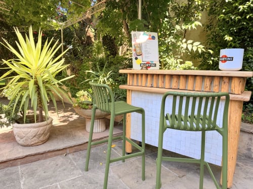 Outdoor bar counter with green chairs in lush garden at Hôtel La Suite, Villeneuve-lès-Avignon
