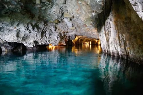 Crystal turquoise cave grotto with golden lighting and limestone cliffs at Hôtel Les Triolets in Châtel, France