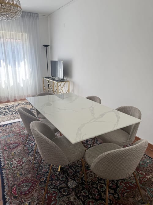 Modern dining area in Rome apartment with marble table, upholstered chairs, oriental rugs, and city view from balcony