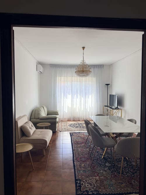 Modern Rome apartment living area with dining table, seating, chandelier, and balcony view at Claudia Apartments