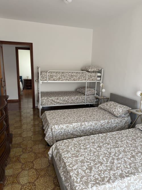 Spacious bedroom at Claudia Apartments Rome with bunk beds, single beds, patterned bedding, and modern furnishings near