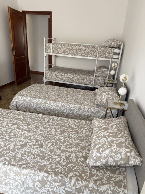 Bright apartment bedroom with two single beds and white bunk bed with beige damask bedding at Claudia Apartments Rome