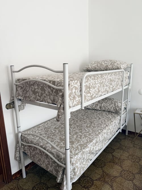 White metal bunk beds with ornate damask bedding in Claudia Apartments Rome dormitory room