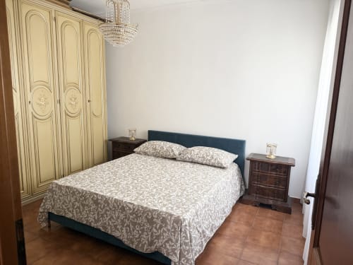 Elegant bedroom at Claudia Apartments Rome with cream wardrobe, dark blue bed, patterned bedding, wooden nightstands, crystal