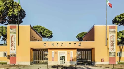 Cinecittà cinema building in Rome near Claudia Apartments, yellow facade with Italian flag