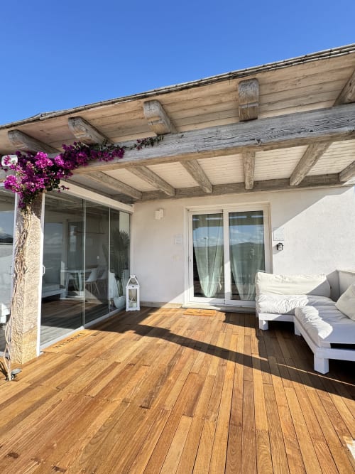 Terrazza Villa Carrie Porto Pozzo con deck in legno, pergolato, buganvillea magenta, arredi bianchi e vista sulle montagne