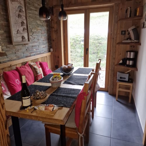 Coin repas cosy de l'appartement Courchevel avec table en bois, banquette rose et portes vitrées sur la montagne