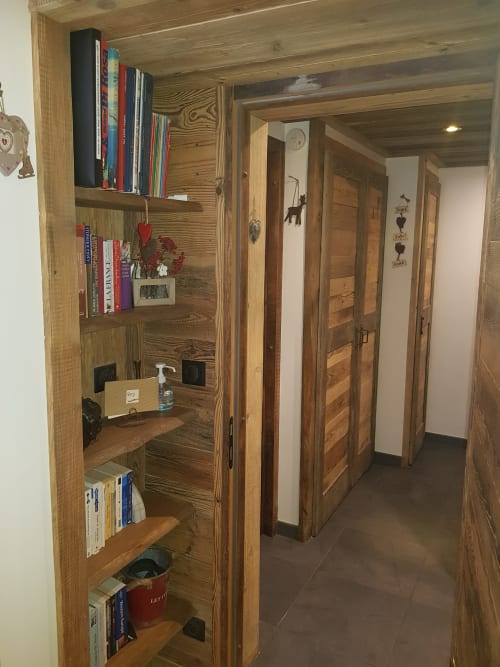 Couloir en bois avec rangements intégrés présentant livres et décoration dans l'appartement Zoppas Courchevel