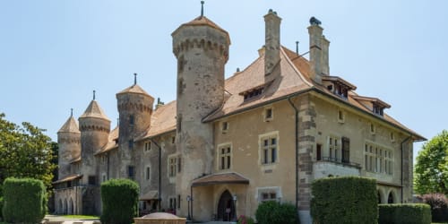 Hôtel Les Triolets castle-style building with towers in Châtel, France surrounded by manicured hedges