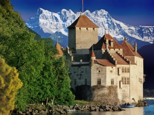 Medieval castle on lake with snow-capped Alps backdrop near Châtel hotel