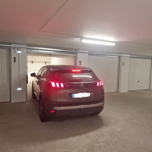 Peugeot rouge garée dans un emplacement numéroté du garage de l'appartement de ski Zoppas Courchevel avec parking résidents