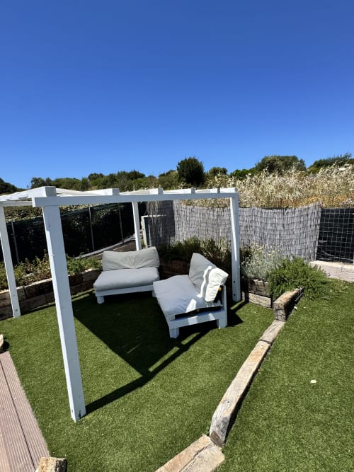 Moderna pergola bianca con lettino lounge e cuscini su erba sintetica, appartamento Villa Carrie Porto Pozzo Gallura
