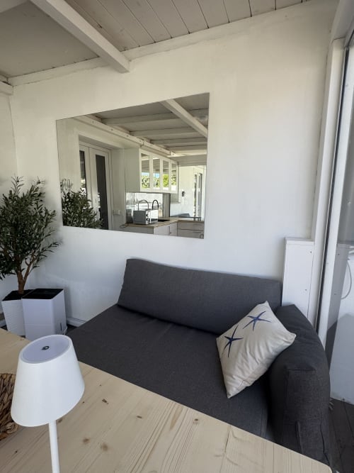 Zona living dell'appartamento CoralBay con divano grigio, travi a soffitto bianche e passavivande verso la cucina a Villa Carrie Porto Pozzo