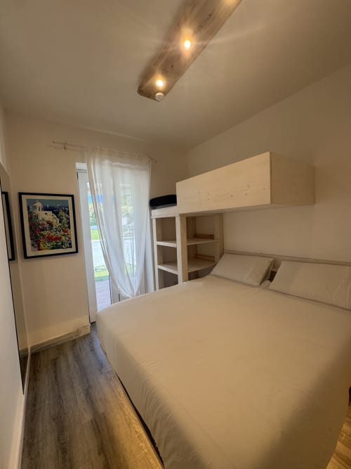 Moderna camera da letto in CoralBay Apartment a Villa Carrie Porto Pozzo, Gallura, con letto matrimoniale, letto a castello e porta in vetro