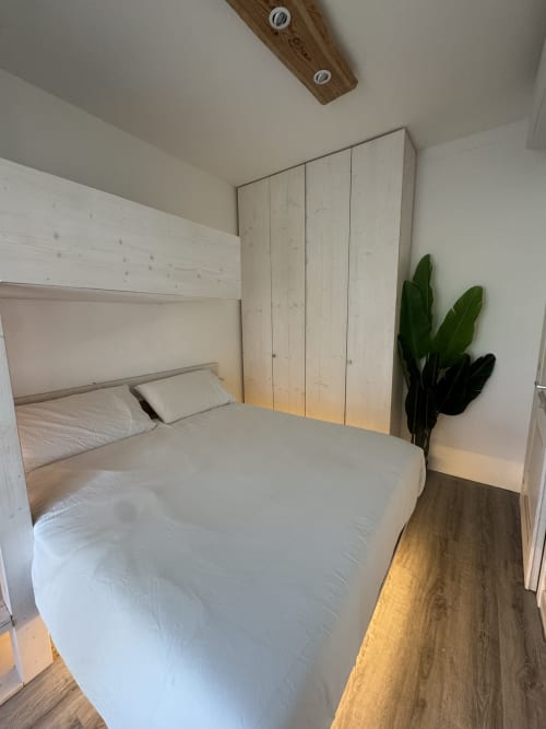 Camera moderna in CoralBay Apartment a Villa Carrie Porto Pozzo, Gallura, con letto bianco, armadio in legno e pianta in vaso