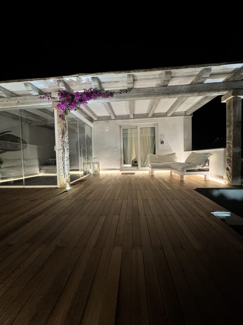Terrazza moderna di Villa Carrie Porto Pozzo con pavimento in legno, pergolato, buganvillea viola, lettini e illuminazione