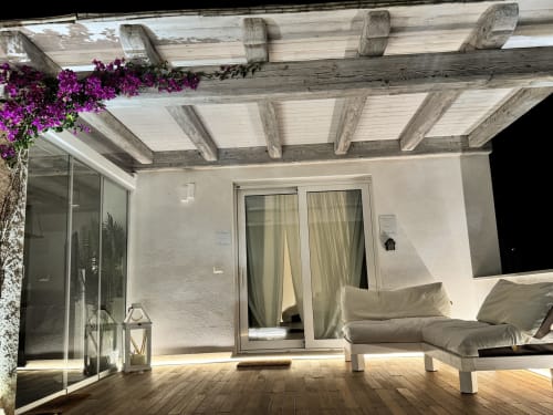 Patio dell'Apartment Starfish a Villa Carrie Porto Pozzo con pergolato in legno, buganvillea viola, zona lounge e accesso
