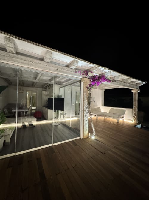 Vista notturna dell'Appartamento Starfish a Villa Carrie Porto Pozzo con patio illuminato, terrazza in legno e buganvillea magenta