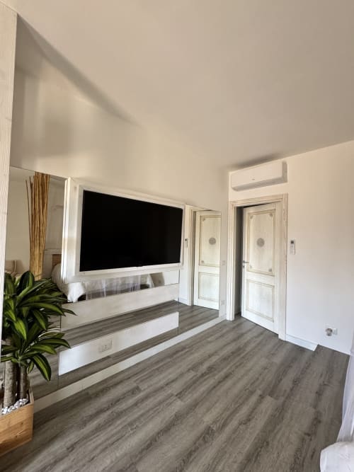 Soggiorno dell'Aparthotel Starfish con TV a parete, mobile multimedia bianco, pavimenti in legno e accesso al patio privato