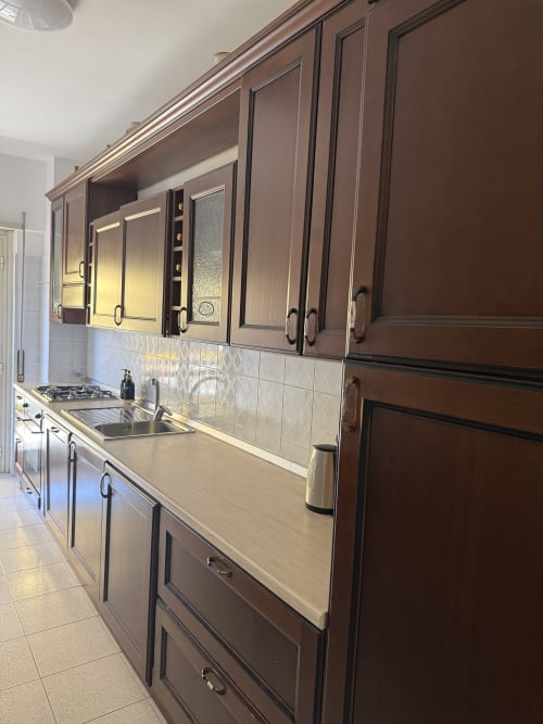 Modern kitchen in Claudia Apartments Rome with brown cabinetry, stainless steel sink, gas cooktop, and tiled backsplash