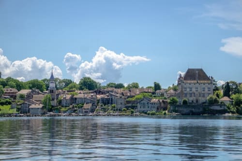 Waterfront village with church spire and mansion overlooking lake, Châtel, France