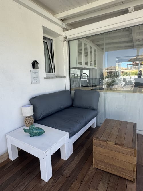Accogliente area lounge della Villa Carrie Porto Pozzo con divano scuro, tavolo bianco e vista mare a Santa Teresa