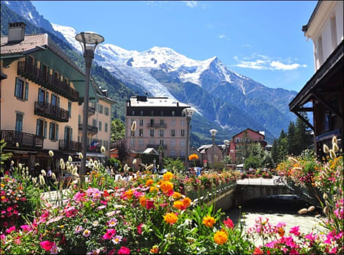 Hôtel Les Triolets in Châtel with colorful flower garden, alpine mountains, and charming village architecture