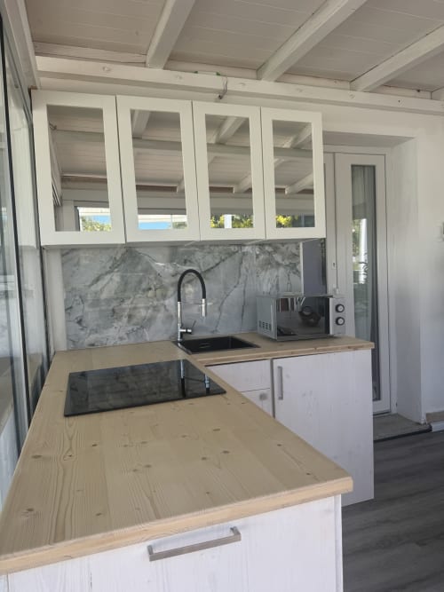 Cucina moderna con piani in legno, mobili bianchi, rivestimento in marmo e vista sul mare a Villa Carrie Porto Pozzo