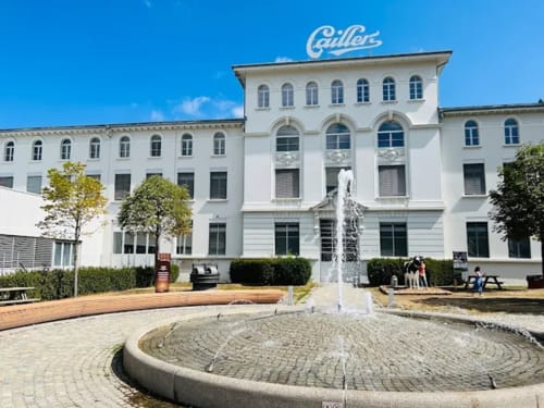 Hôtel Les Triolets courtyard in Châtel featuring white building with Gillet sign and central fountain