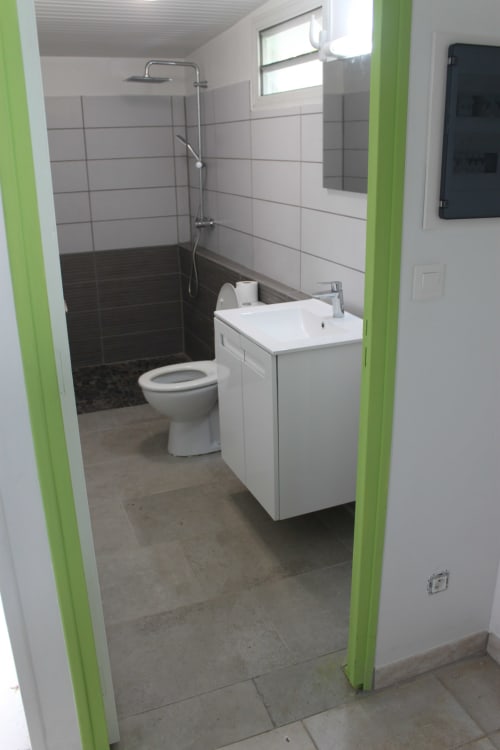 Salle de bains moderne à la Résidence B&L Lagon avec vasque blanche, toilettes et douche à l'italienne aux carreaux sombres à Sainte-Luce