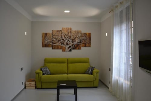 Salón moderno en Apartamentos RJ26 León con sofá verde lima, obra de arte arbórea y vistas a la ciudad