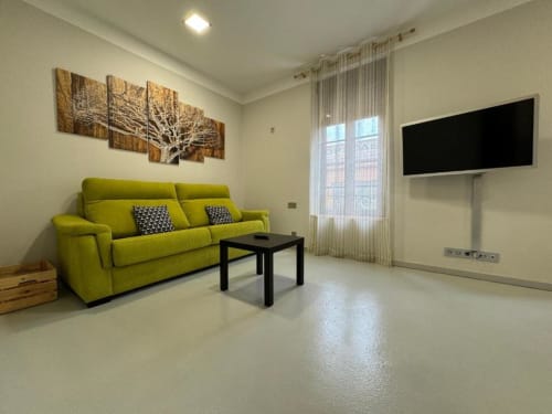 Sala de estar moderna en Apartamentos RJ26 León con sofá verde lima, TV de pared y decoración contemporánea