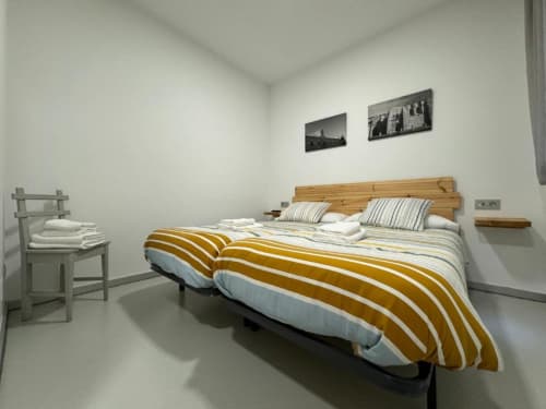 Dormitorio moderno en Apartamentos RJ26 León con cama de madera, ropa de cama a rayas y mobiliario minimalista