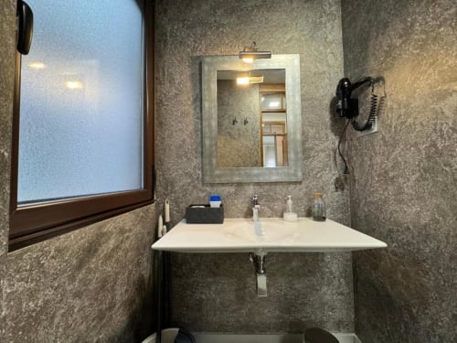 Baño moderno en Apartamentos RJ26 León con lavabo mural, espejo iluminado y paredes de azulejos grises