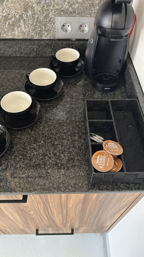Estación de café con tazas negras, cafetera Krups y cápsulas Dolce Gusto en Apartamentos RJ26 León