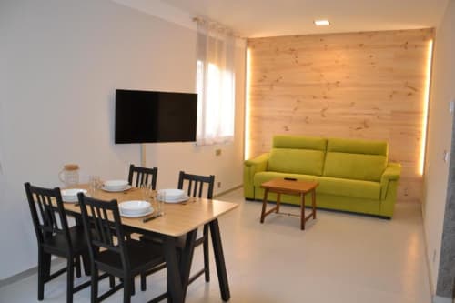 Sala de estar moderna con mesa de comedor, sofá verde y pared de madera en Apartamentos RJ26 León