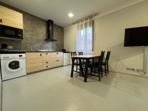 Moderna zona de cocina-comedor en Apartamentos RJ26 León con muebles de madera, mesa de comedor y vistas a la ciudad